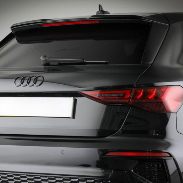 A black Audi car's rear showcases its logo and taillights. The vehicle is stationary, possibly in a studio setting with a neutral background.
