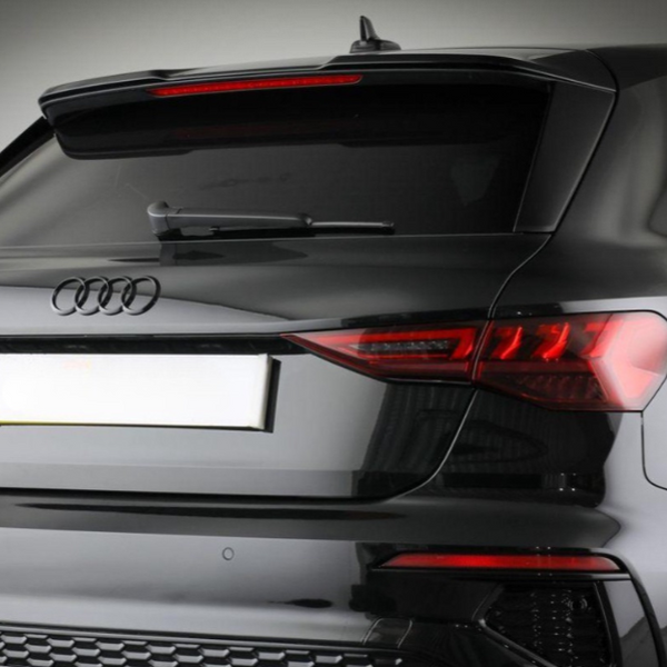 A black Audi car's rear showcases its logo and taillights. The vehicle is stationary, possibly in a studio setting with a neutral background.