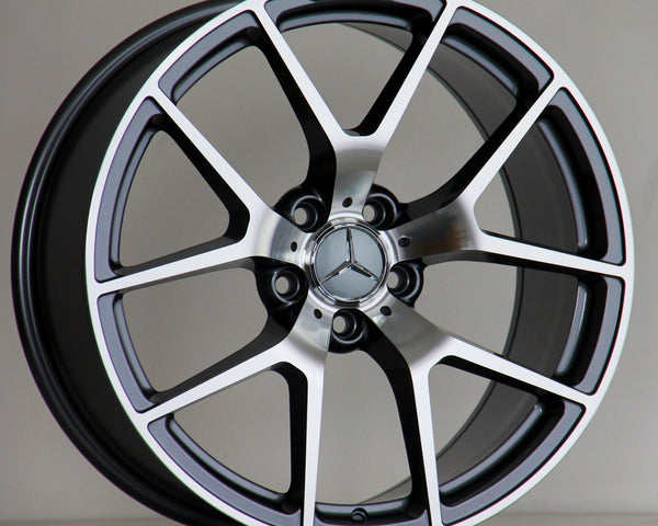 A Mercedes-Benz alloy wheel stands upright, featuring a five-spoke design with a polished finish. The AMG logo is inscribed at the top. It's set against a neutral background.