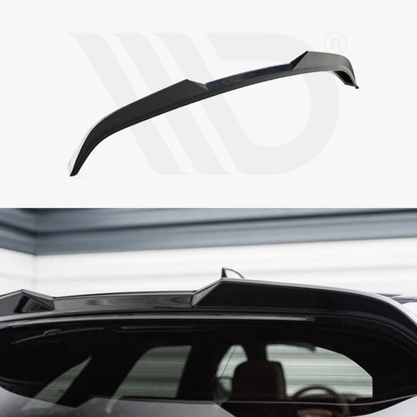 Black car roof spoiler installed on the rear of a vehicle, enhancing aerodynamics. The setting is a garage with gray and white walls, creating a sleek, modern atmosphere.