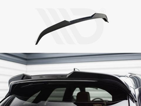 Black car roof spoiler installed on the rear of a vehicle, enhancing aerodynamics. The setting is a garage with gray and white walls, creating a sleek, modern atmosphere.