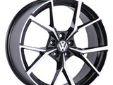 A black and silver alloy wheel with a geometric spoke design is displayed, featuring a central emblem with 
