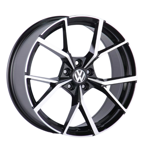 A black and silver alloy wheel with a geometric spoke design is displayed, featuring a central emblem with "VW." The wheel is positioned against a plain white background.