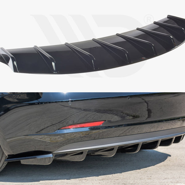 A black car diffuser with fin-like structures shown detached above, and attached below to the rear bumper of a black car parked on a concrete surface. No text present.