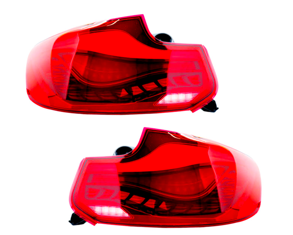 Two red car taillights, unlit, are displayed against a plain white background. Each taillight features intricate internal details and black mounting connectors.
