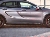 A gray car with red accented wheels is parked on a patterned pavement. The vehicle's side features a bold contour design and visible text 