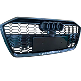 A black car grille displays three circular emblems at the top and “quattro” text at the bottom, featuring a honeycomb pattern.