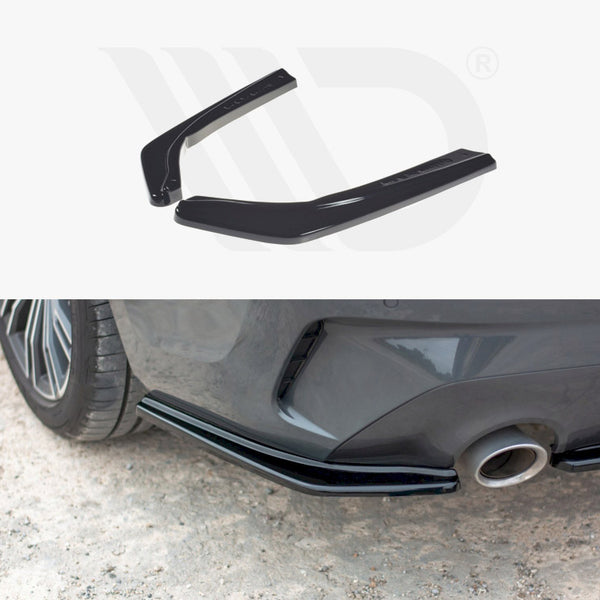 Two black car rear spoilers are displayed above an image showing them installed on a gray car's rear bumper next to the exhaust pipe, on a gravel surface.