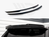 Two black spoilers are displayed; one is installed above a car's rear window in a garage-like setting with white walls.