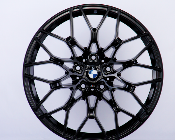 A black, intricately designed car wheel rim with the BMW logo at the center against a plain white background.