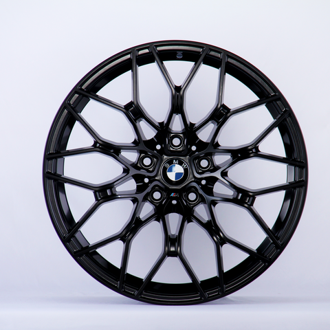 A black, intricately designed car wheel rim with the BMW logo at the center against a plain white background.