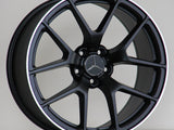 A black alloy wheel with a five-spoke design, featuring a Mercedes-Benz logo in the center and 