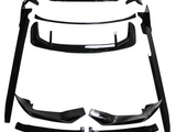 Black car body kit components, including spoilers and side skirts, are arranged on a white background. The parts are neatly organized, showcasing their glossy finish and aerodynamic design.