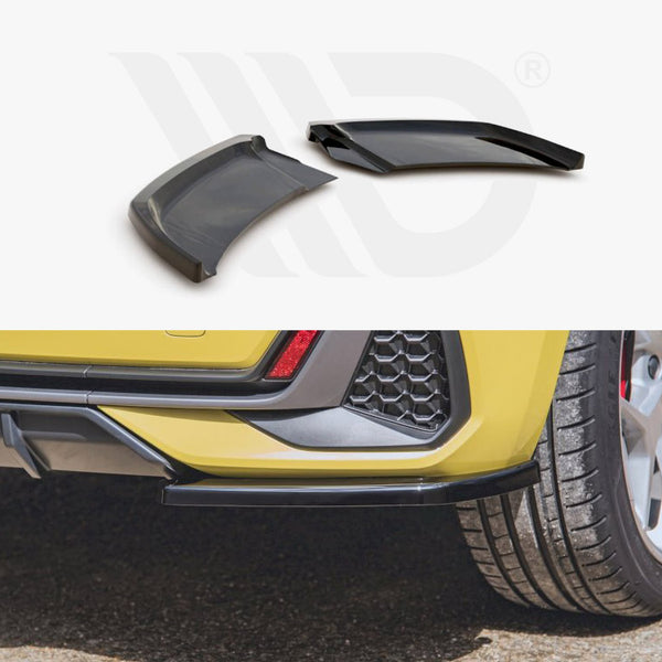 Car rear bumper with two angular black attachments lying detached. The yellow vehicle is parked on asphalt, showcasing silver wheels and a honeycomb-patterned section. Partial logo watermark in the background.