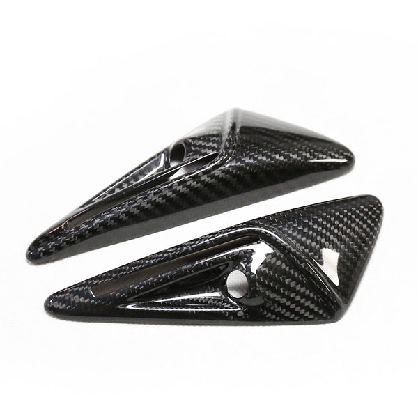 Two carbon fiber objects feature a sleek, aerodynamic design with pointed ends and small circular cutouts, set against a plain white background.