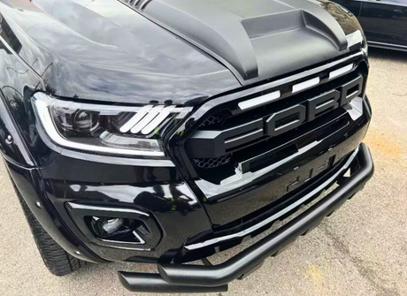 A black truck features prominently, showcasing its front grille with large letters spelling "FORD," and LED headlights, parked on a paved surface.