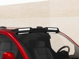 A red car with a roof rack mounted, holding two rectangular lights. The vehicle is parked against a plain, beige wall, seen from a slightly elevated front angle.
