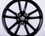 A shiny black, multi-spoke alloy wheel featuring a central Volkswagen logo, displayed against a plain white background.