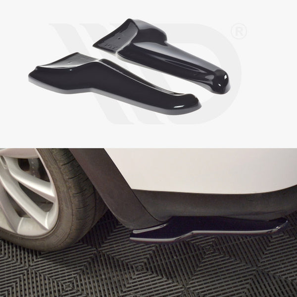 Black automotive mud flaps are displayed; one is installed on a white car's wheel arch near a tire, while the other is shown separately. The background features a textured black mat.