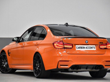 An orange BMW M3 is parked indoors, showcasing a sleek design and black wheels. The license plate reads 