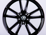 A glossy black alloy wheel with a multi-spoke design, featuring a Volkswagen emblem at the center, set against a plain white background.
