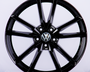 A glossy black alloy wheel with a multi-spoke design, featuring a Volkswagen emblem at the center, set against a plain white background.