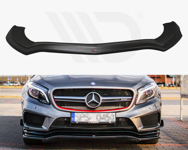 A black front splitter is displayed above a silver Mercedes-Benz sports car with a prominent grille, parked on a paved area surrounded by buildings and cars.