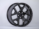 A glossy black alloy wheel with a multi-spoke design is displayed upright against a plain white background, showcasing its smooth and polished surface.