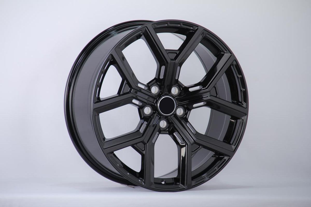 A glossy black alloy wheel with a multi-spoke design is displayed upright against a plain white background, showcasing its smooth and polished surface.