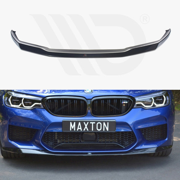 A black car front lip spoiler displayed above a blue car with a distinctive grille and headlights. The car, parked on a road, has a license plate reading "MAXTON."