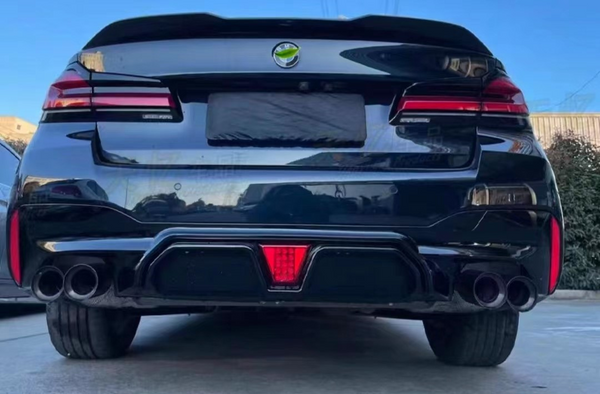 A sleek black car is parked, showcasing dual exhausts and distinctive rear lights, in a sunny outdoor setting with clear blue skies and nearby shrubbery.