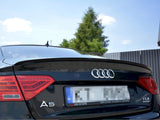 The rear of a black Audi A5 displays its logo and taillights, parked outdoors. Plate text reads: 