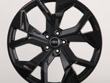 A glossy black car wheel features a five-spoke design with intersecting shapes, prominently displaying the Audi logo at the center on a plain, light background.