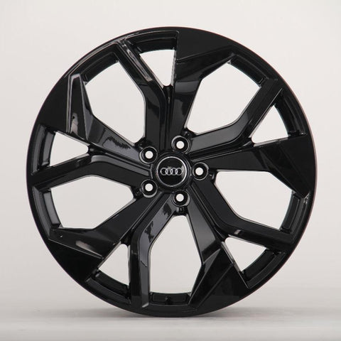 A glossy black car wheel with multiple spokes featuring the Audi logo at its center, displayed against a plain white background.
