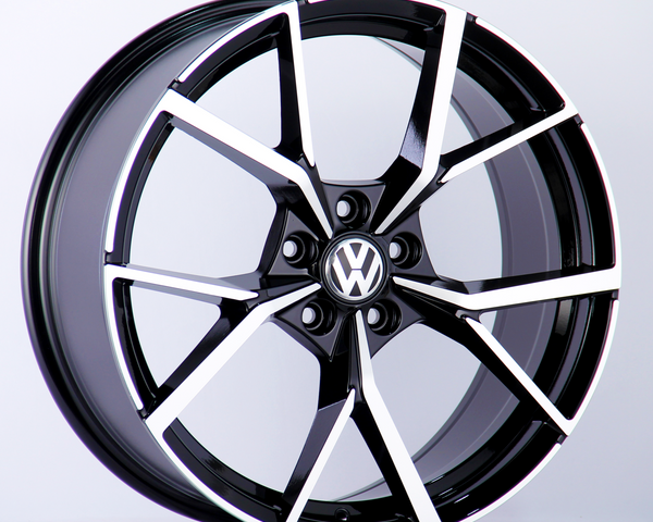 A black and silver alloy wheel with a distinctive star pattern and a "VW" logo is set against a plain white background.
