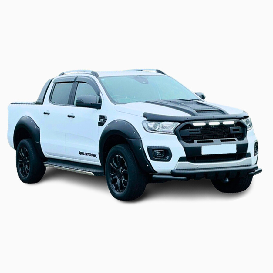 A white pickup truck with black accents is parked on a white background. It features bold, aggressive styling with flared wheel arches and sporty side steps. Text: "WILDTRAK".