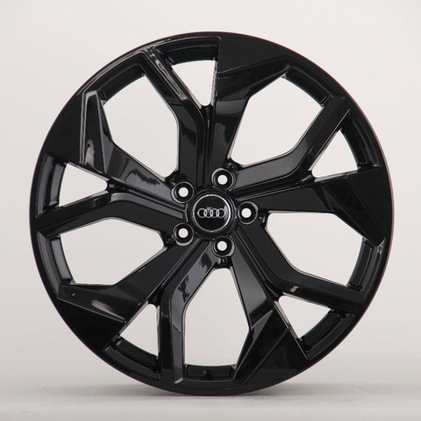A glossy black car wheel rim with five split spokes, featuring the Audi logo in the center, is displayed against a plain white background.