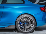 A blue car, focusing on its rear quarter panel and wheel, is parked on a concrete surface. The tire reads 