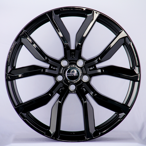 A shiny black alloy wheel features prominent spokes and a "Range Rover" logo at its center, set against a plain white background.