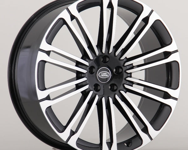 A black and silver Land Rover alloy wheel with multiple spokes is displayed against a plain gray background. The center cap features the "LAND ROVER" logo in white text.