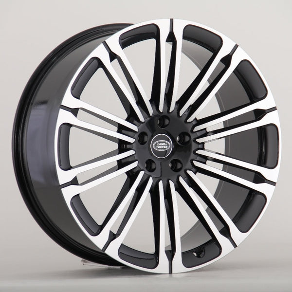 A black and silver Land Rover alloy wheel with multiple spokes is displayed against a plain gray background. The center cap features the "LAND ROVER" logo in white text.