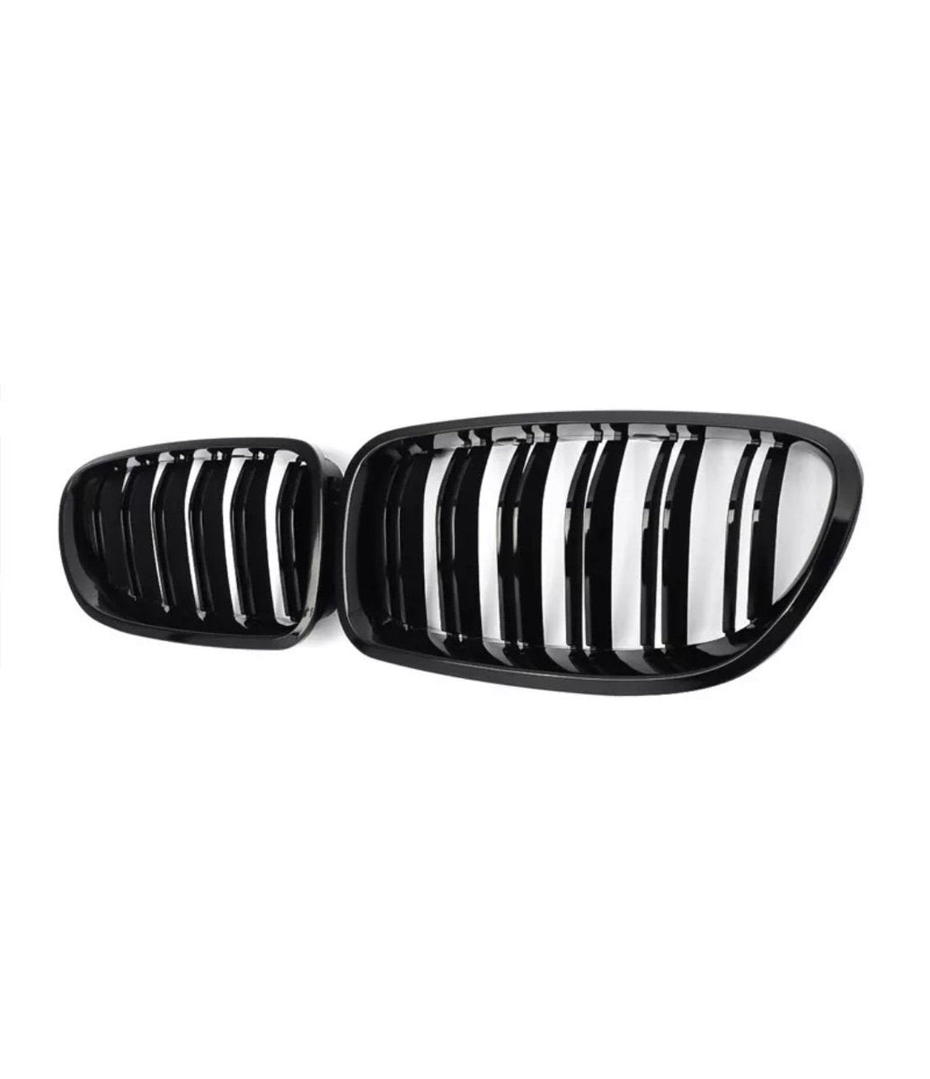 A pair of black car grilles with vertical slats, positioned side by side, set against a plain white background.