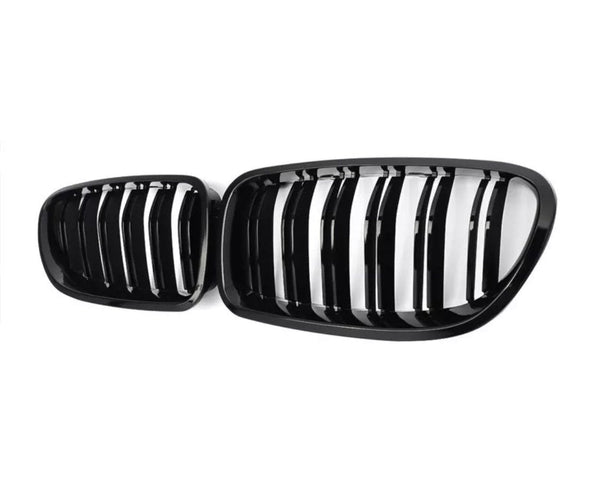 A pair of black car grilles with vertical slats, positioned side by side, set against a plain white background.