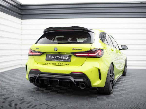 A bright yellow BMW M135i is parked in a white, enclosed garage. The license plate reads "#MAXTONIZED, MAXTON DESIGN", and the car features a sporty rear diffuser and black wheels.