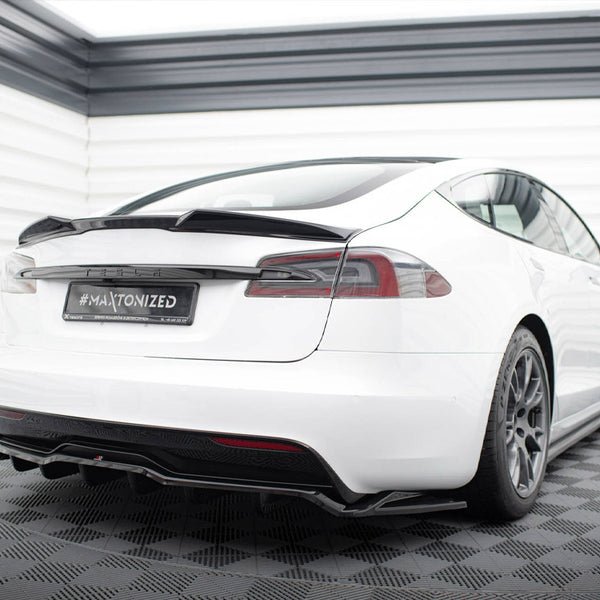 A white car with a sporty design is parked on a checkered floor. The back license plate reads "#MAXTONIZED." It's in a white, enclosed space with striped walls.