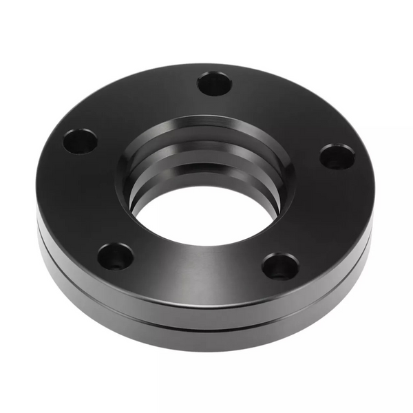 A black metal flange with five bolt holes is resting on a white background. Its circular shape features a central hollow section with a threaded interior.