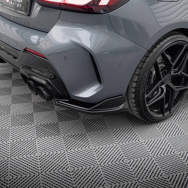 Gray car rear, showcasing a dual exhaust and black alloy wheel, parked on a patterned surface. Text on the license plate reads: "R1M DESIGN, wheels, safety-lip, carbonfiber, vanadiumwheels.com."
