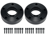 Two black circular wheel spacers with multiple bolt holes are placed side by side. Below each spacer, a row of black bolts and nuts is neatly aligned on a plain white background.