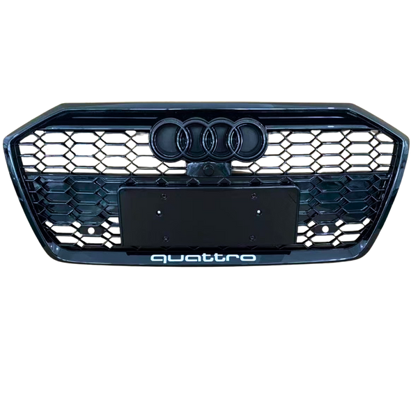 A front car grille displays the Audi logo with four rings and a honeycomb pattern. Below, "quattro" text is located. The background is plain, emphasizing the grille design.