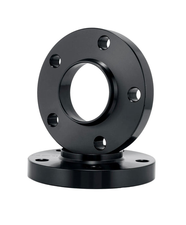 A black metal flange with a central hole and multiple bolt holes sits upright on another similar flange, set against a plain white background.